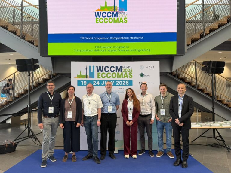 Group photo of TRR 402 DediGrad researchers in front of the WCCM–ECCOMAS 2026 conference banner in Munich.